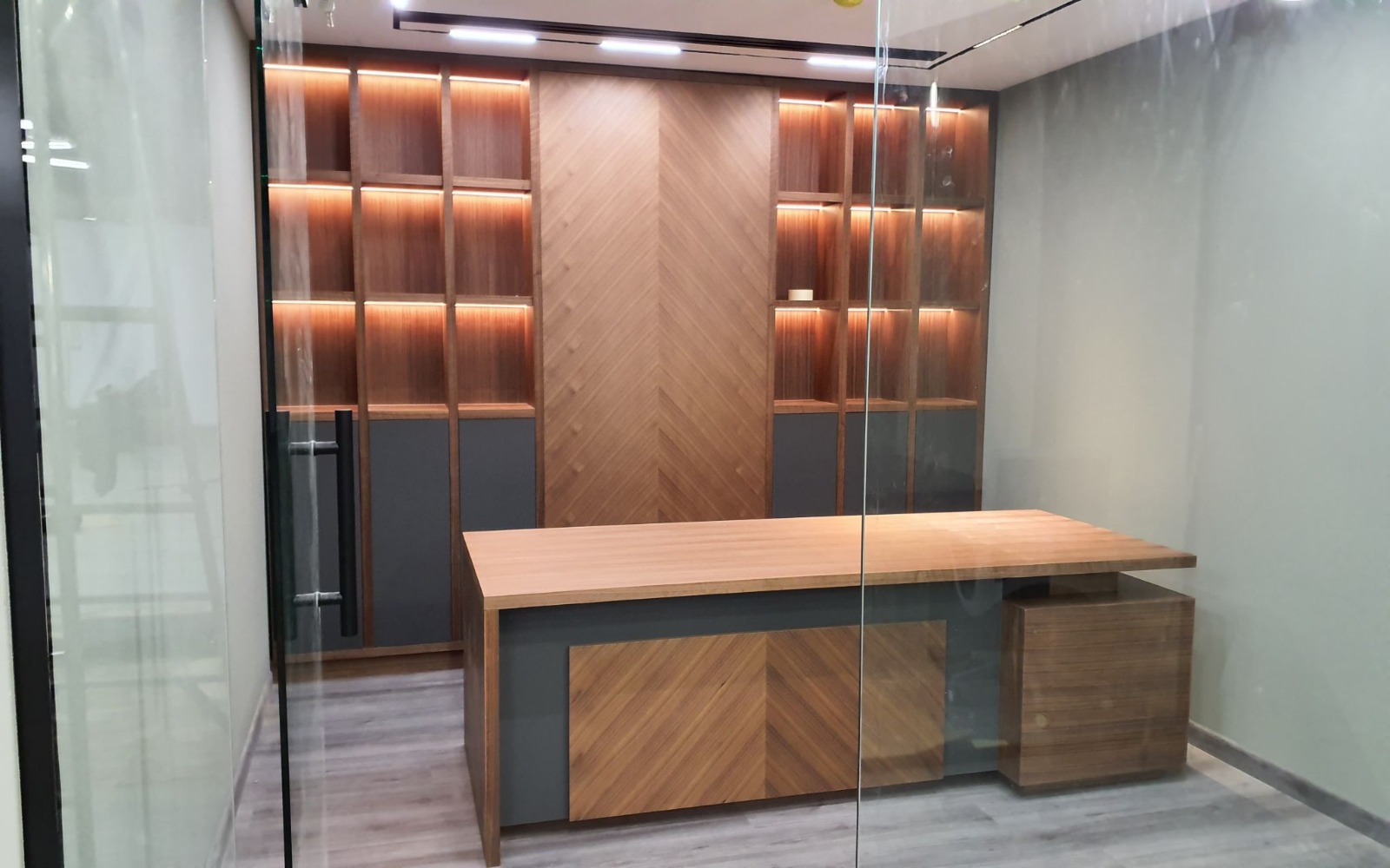 Bespoke executive desk with backlit walnut bookshelves